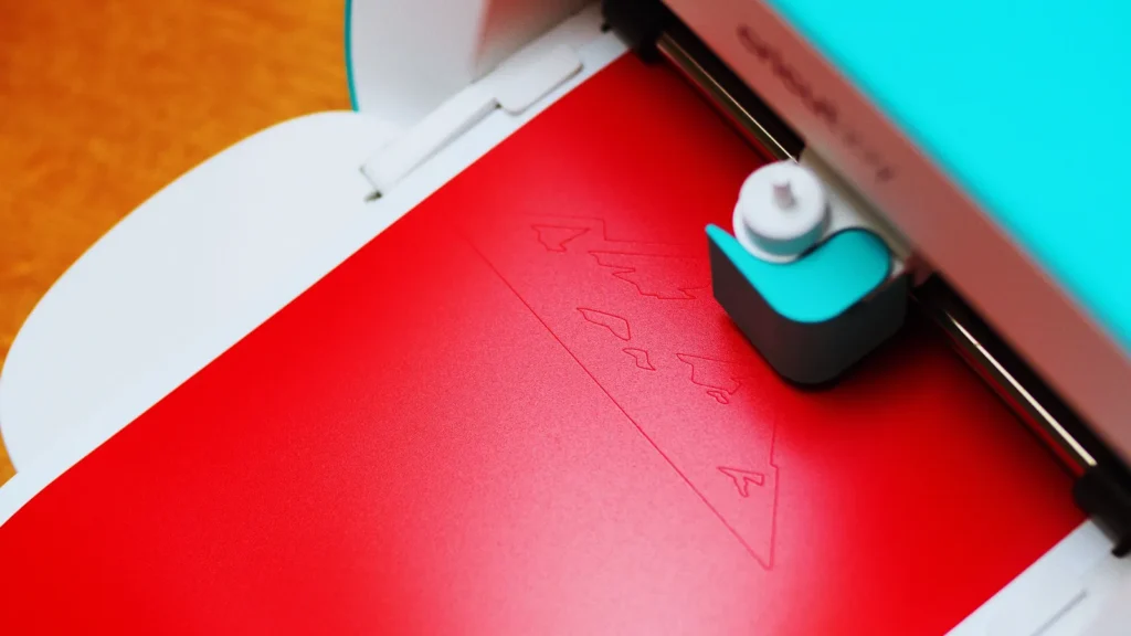 Plotter de recorte cortando material vermelho em oficina