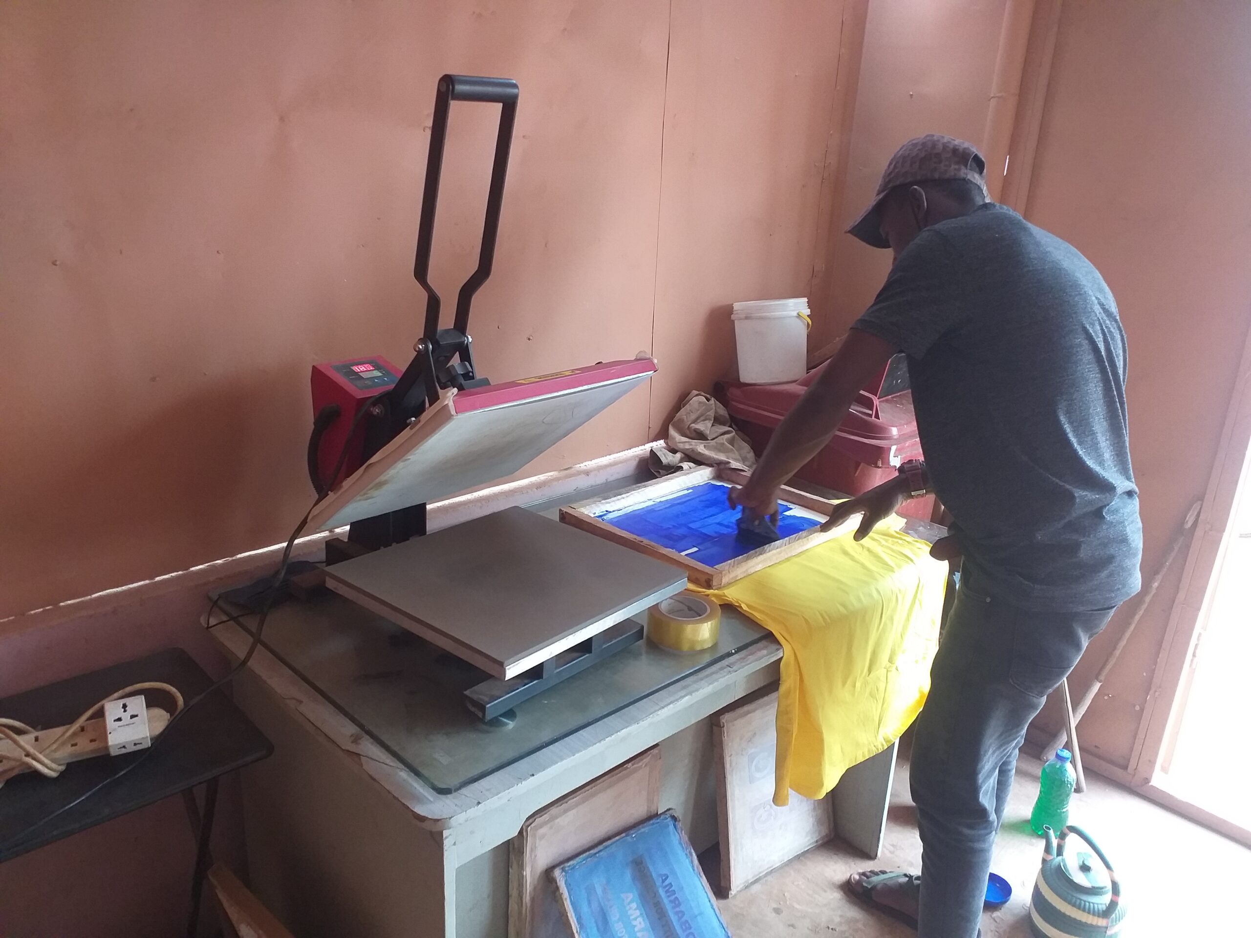 Operador trabalhando com prensa térmica para personalização de camiseta
