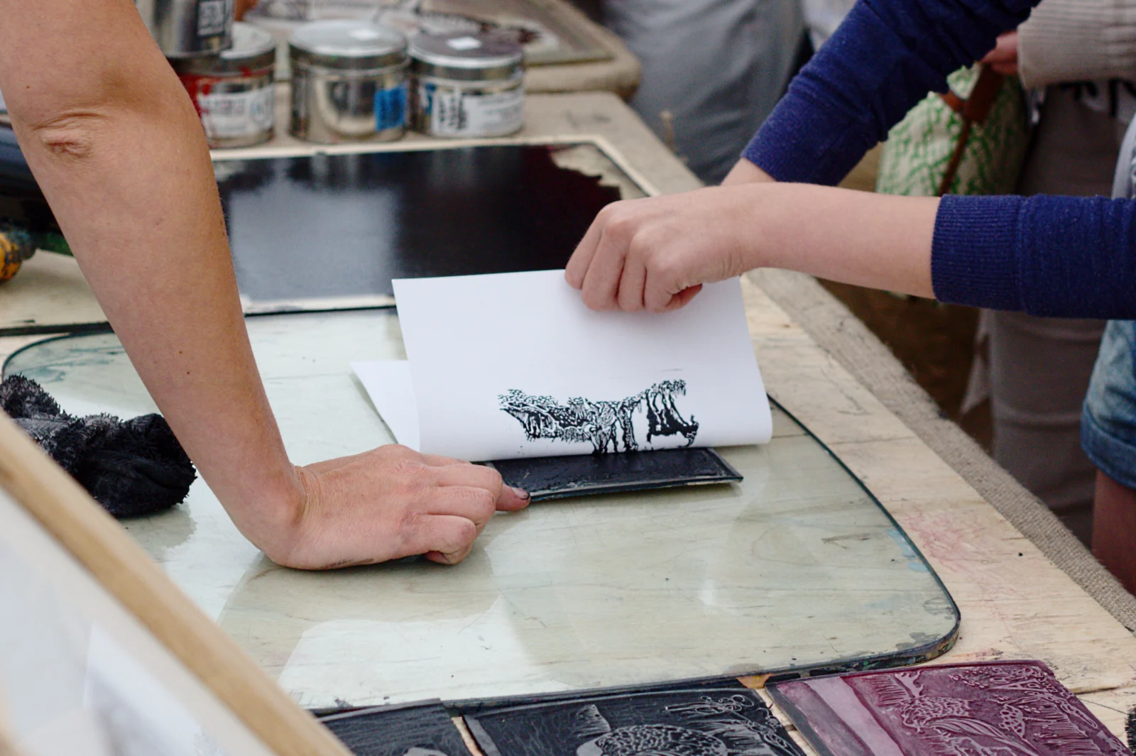 Pessoa levantando o papel após imprimir uma matriz de linóleo em uma linogravura